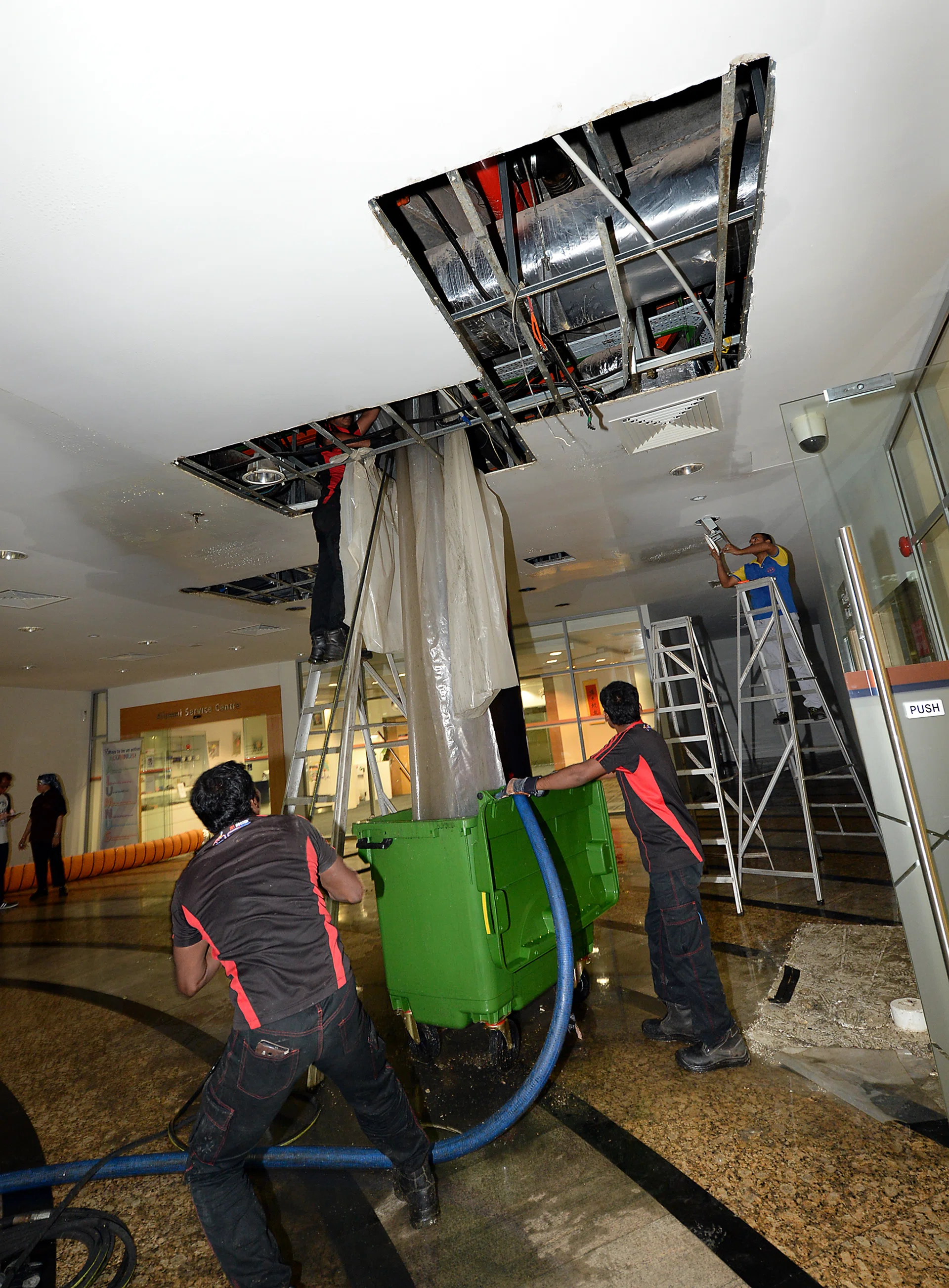 CLEANING UP: A kitchen waste pipe in Shaw Foundation Alumni House burst, causing waste water to leak from the ceiling to the floor of the first storey. TNP PHOTOS: CHOO CHWEE HUA