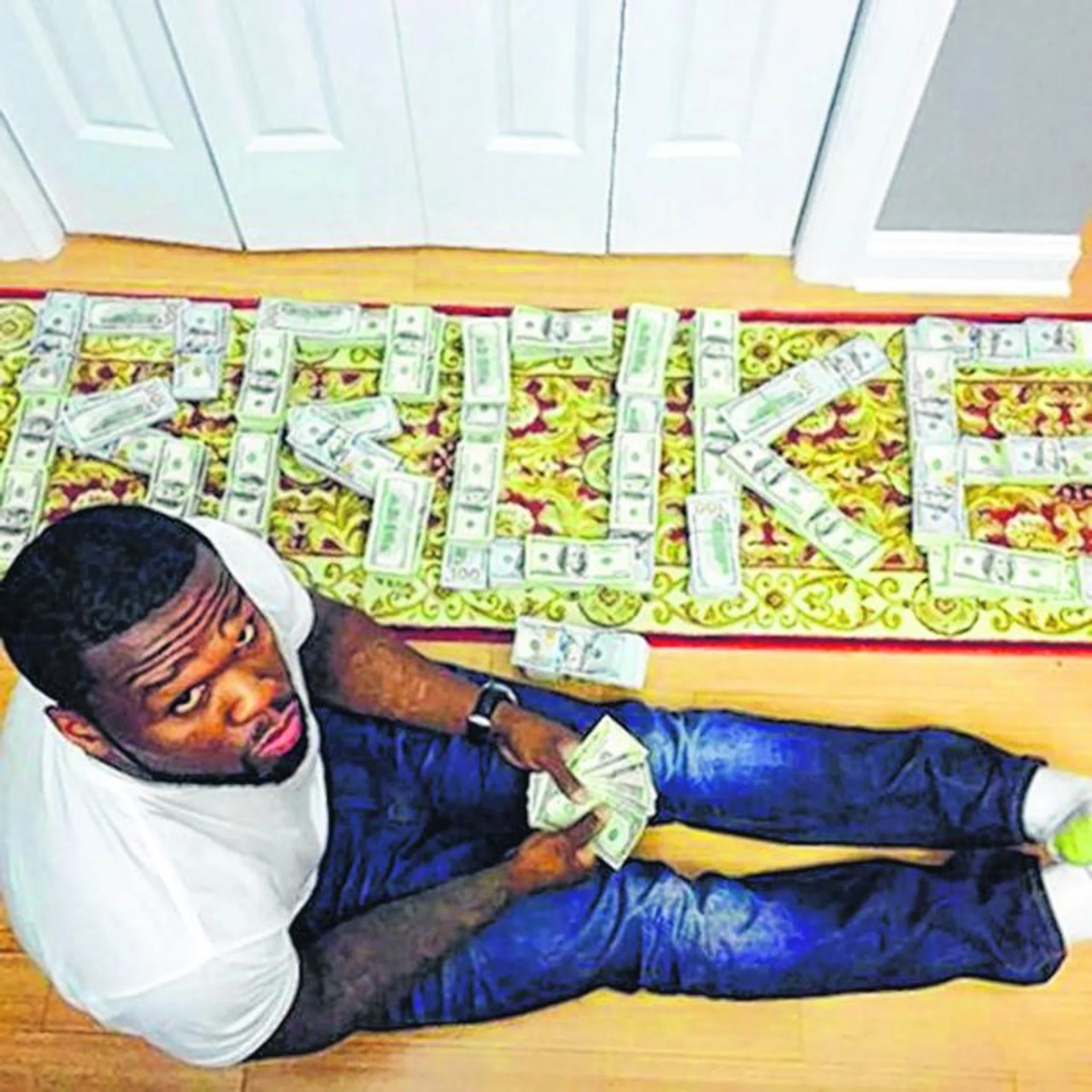 BOLD: 50 Cent with bundles of cash arranged to spell the word "broke".
