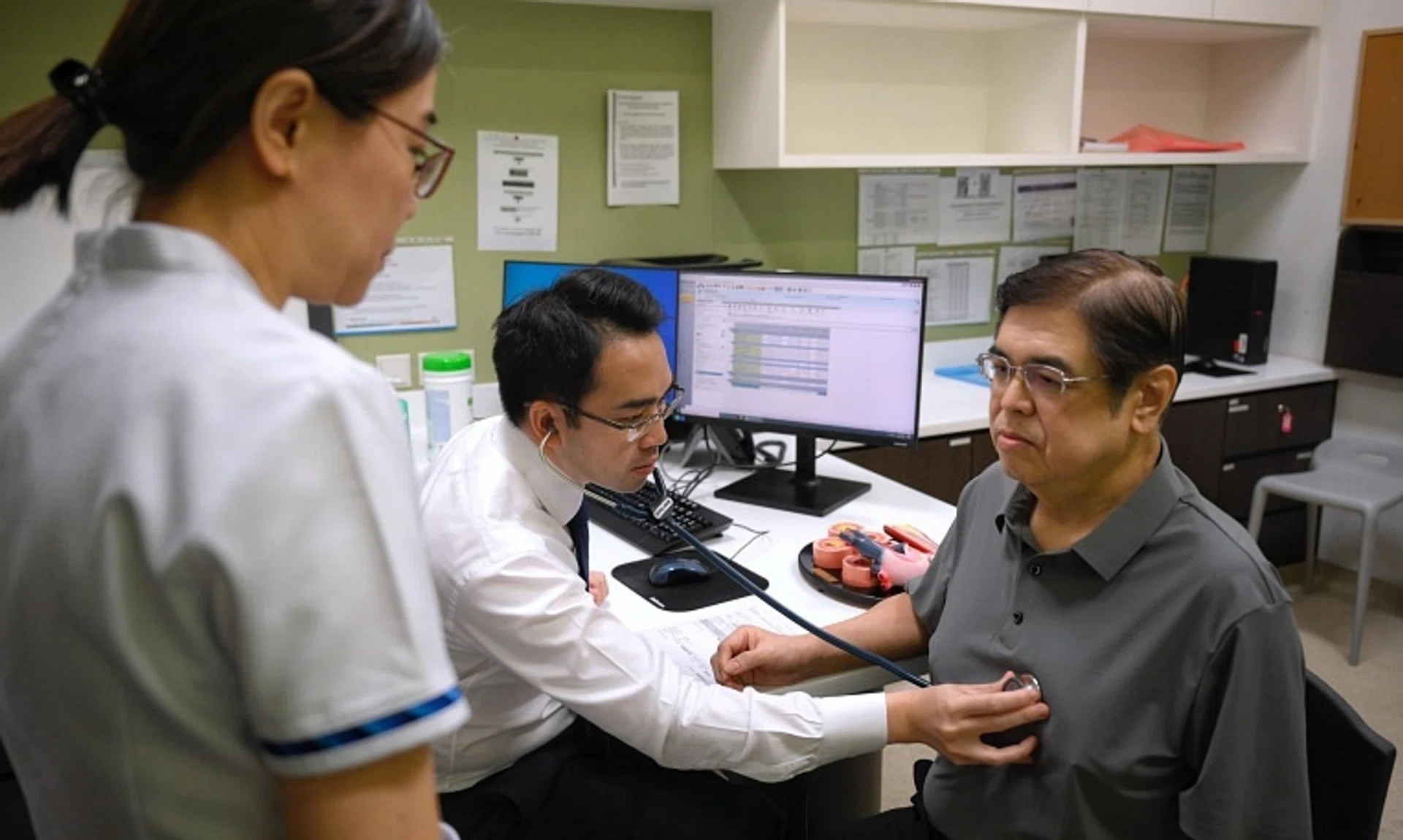 Associate Professor Kenneth Chew (centre), with senior staff nurse Ivy Tan, checking on patient Lam Theam Fatt, who is part of the Heartlanders initiative.