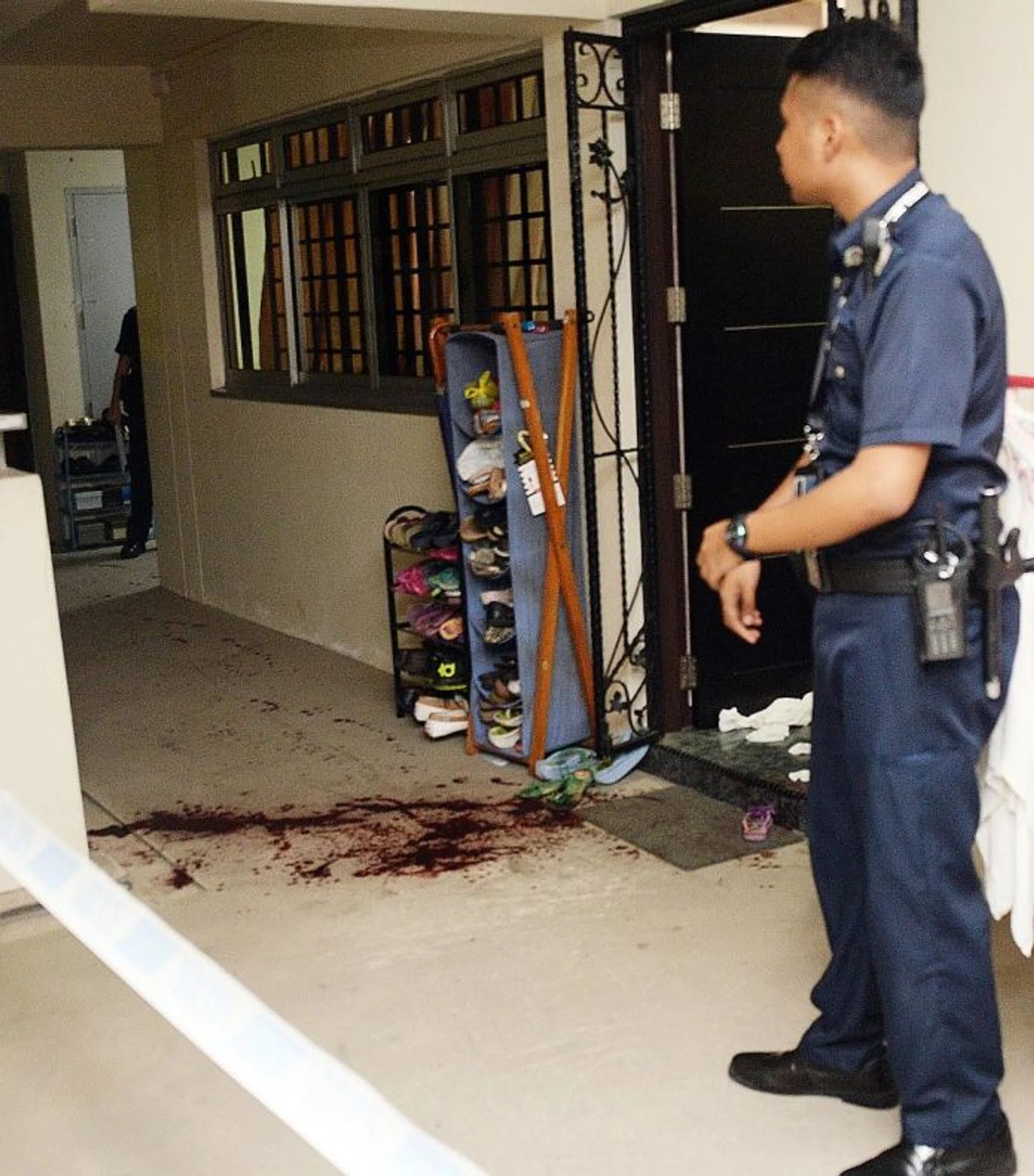 BLOODY: A policeman stands near the bloodstains outside the HDB unit where the maid works.