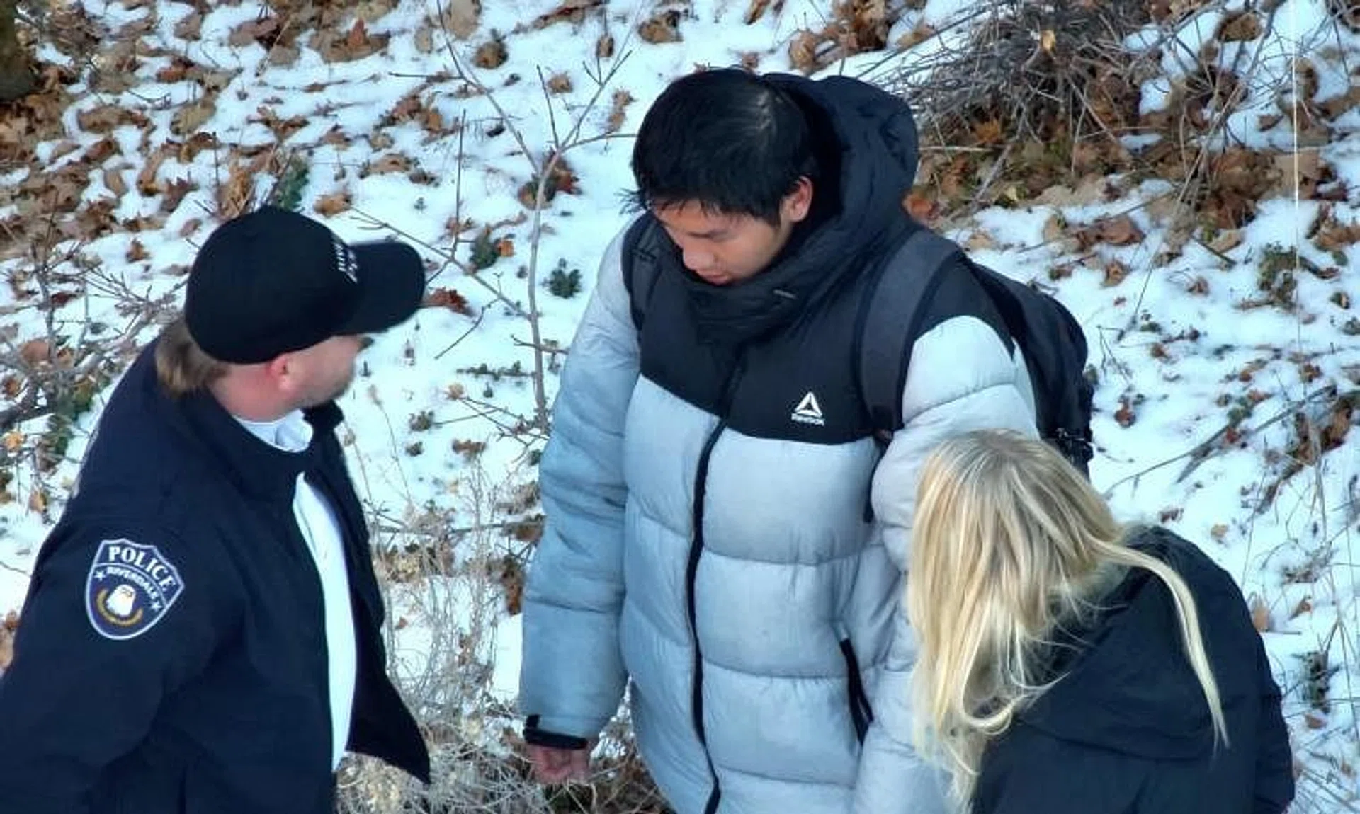 The authorities speaking to Mr Kai Zhuang (centre) near the site where he was found in the mountains near Brigham City, Utah.