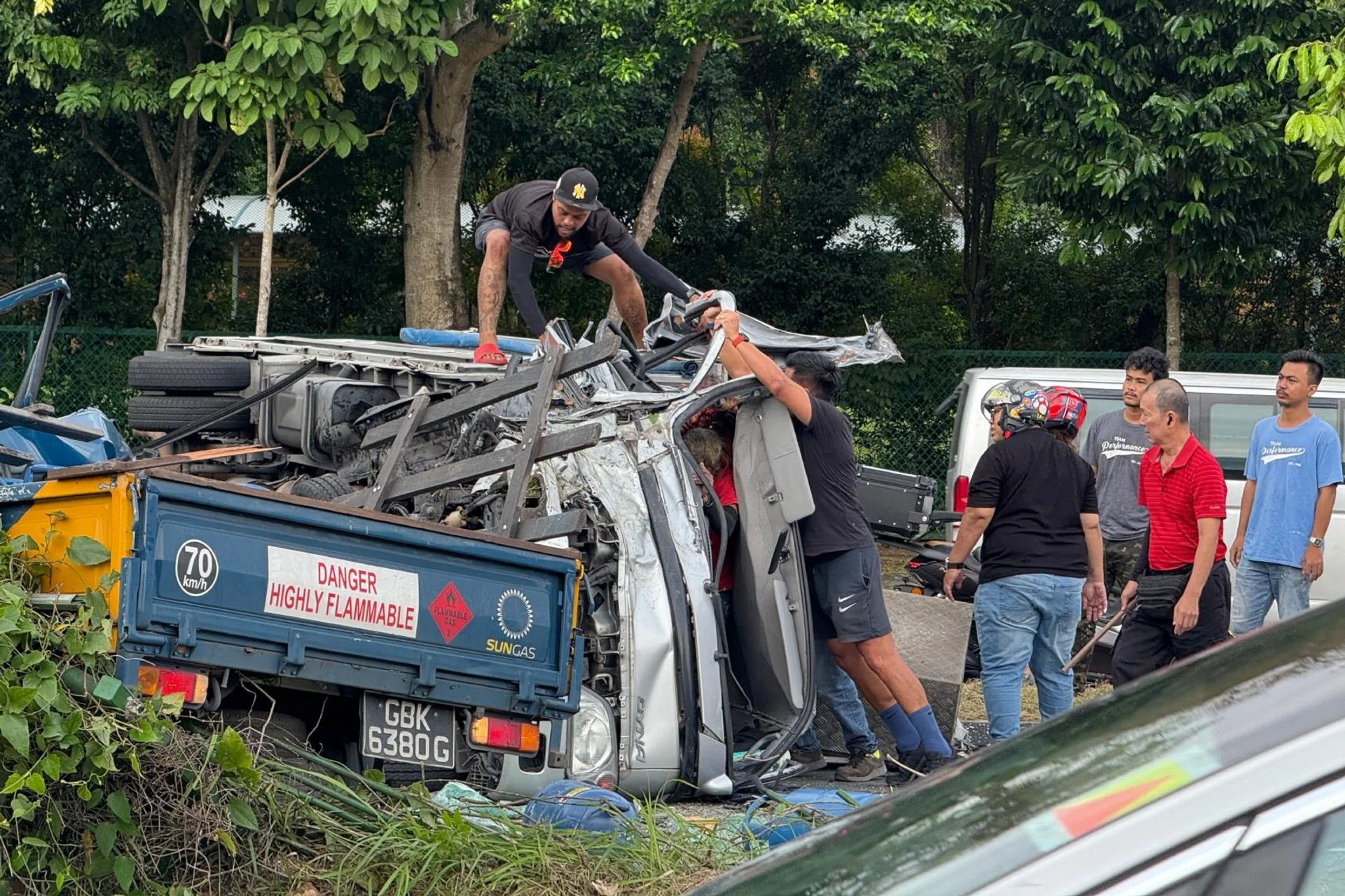 Mr Addy Izwan (pictured on top of the lorry) tries unsuccessfully to open the door of a lorry on its side on May 27.