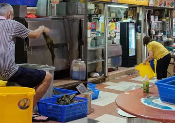 Diner repulsed by hawker who leaves vegetables on floor while another washes area