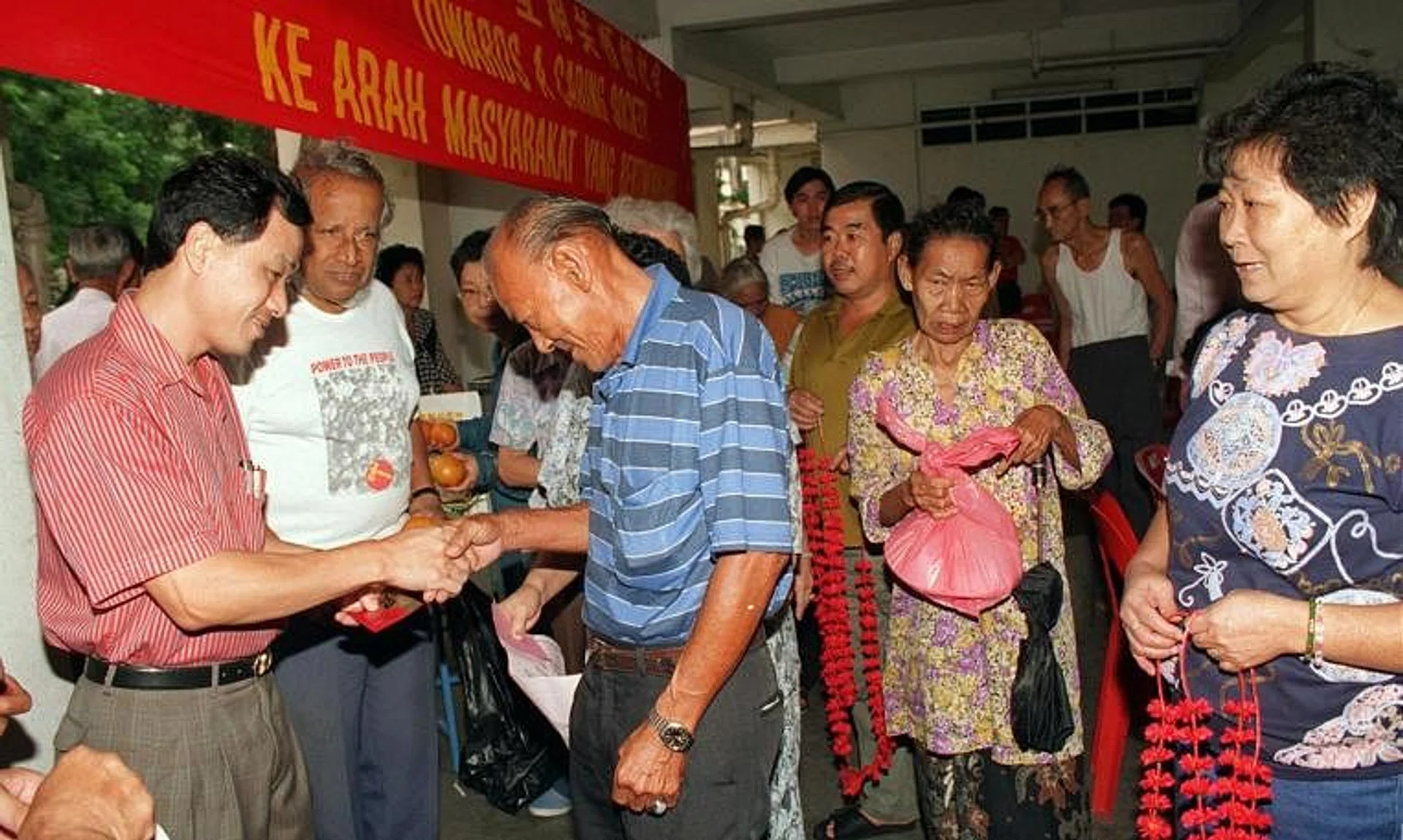 Workers' Party MP Low Thia Khiang (left) and party secretary-general J.B. Jeyaretnam (next to him) distributing hongbao and food hampers to poor, elderly residents in Hougang.