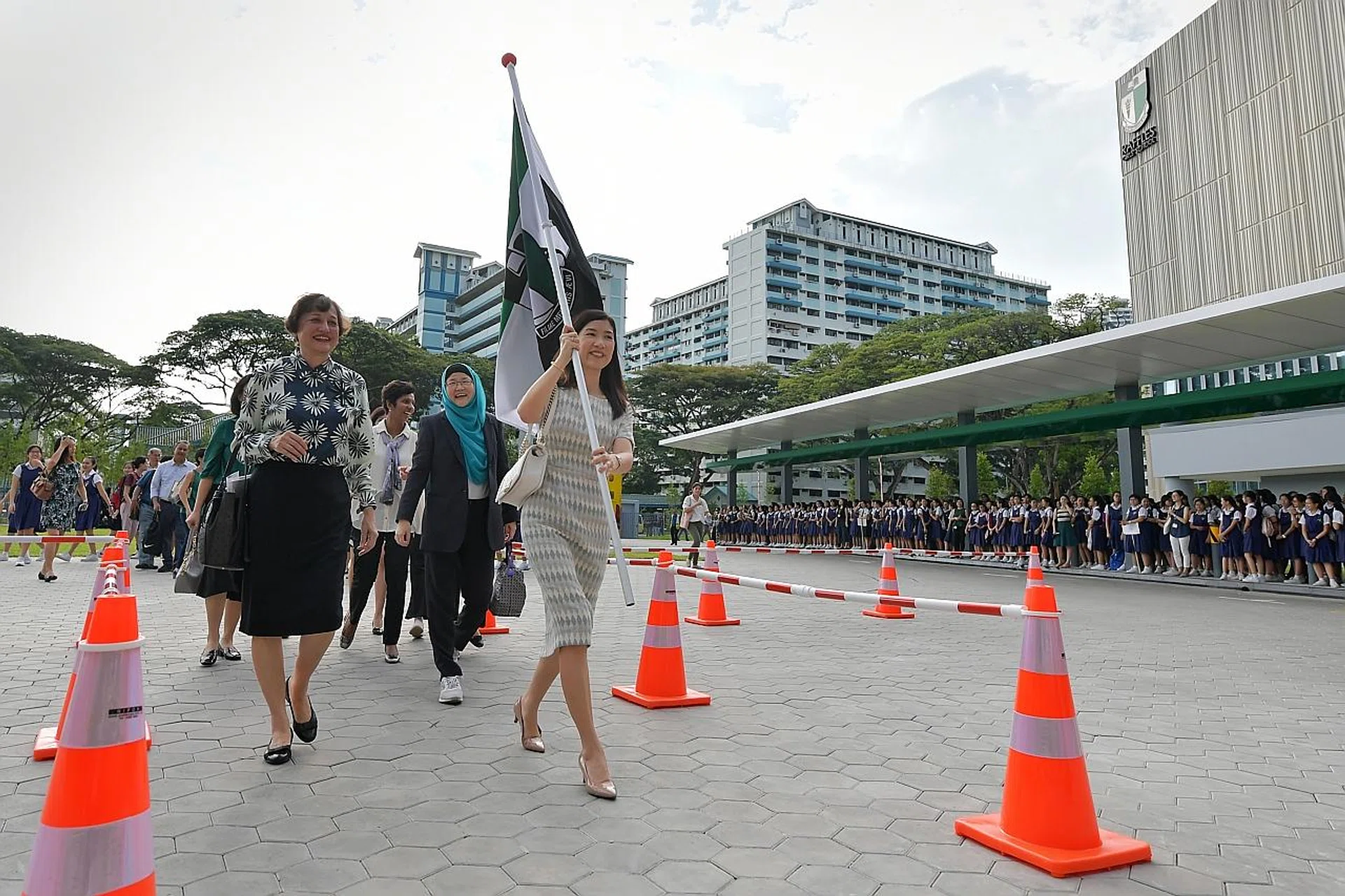 RGS principal and alumna, Mrs Poh Mun See, carrying the school flag to the new school campus. 