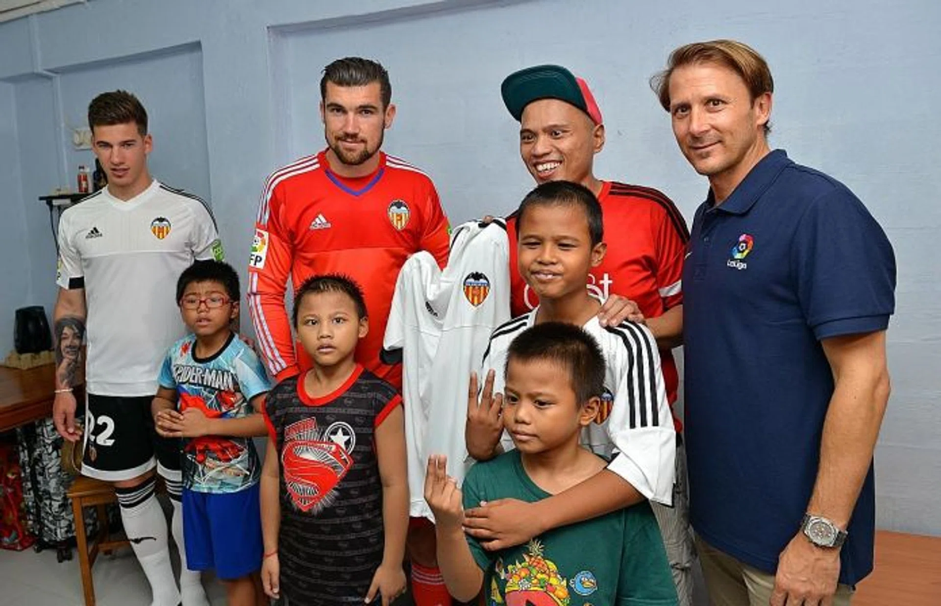STARS PAY VISIT: Valencia striker Santi Mina (left), goalkeeper Mathew Ryan (second from left) and former midfielder Gaizka Mendieta (right) visit a family at their home at Beo Crescent.
