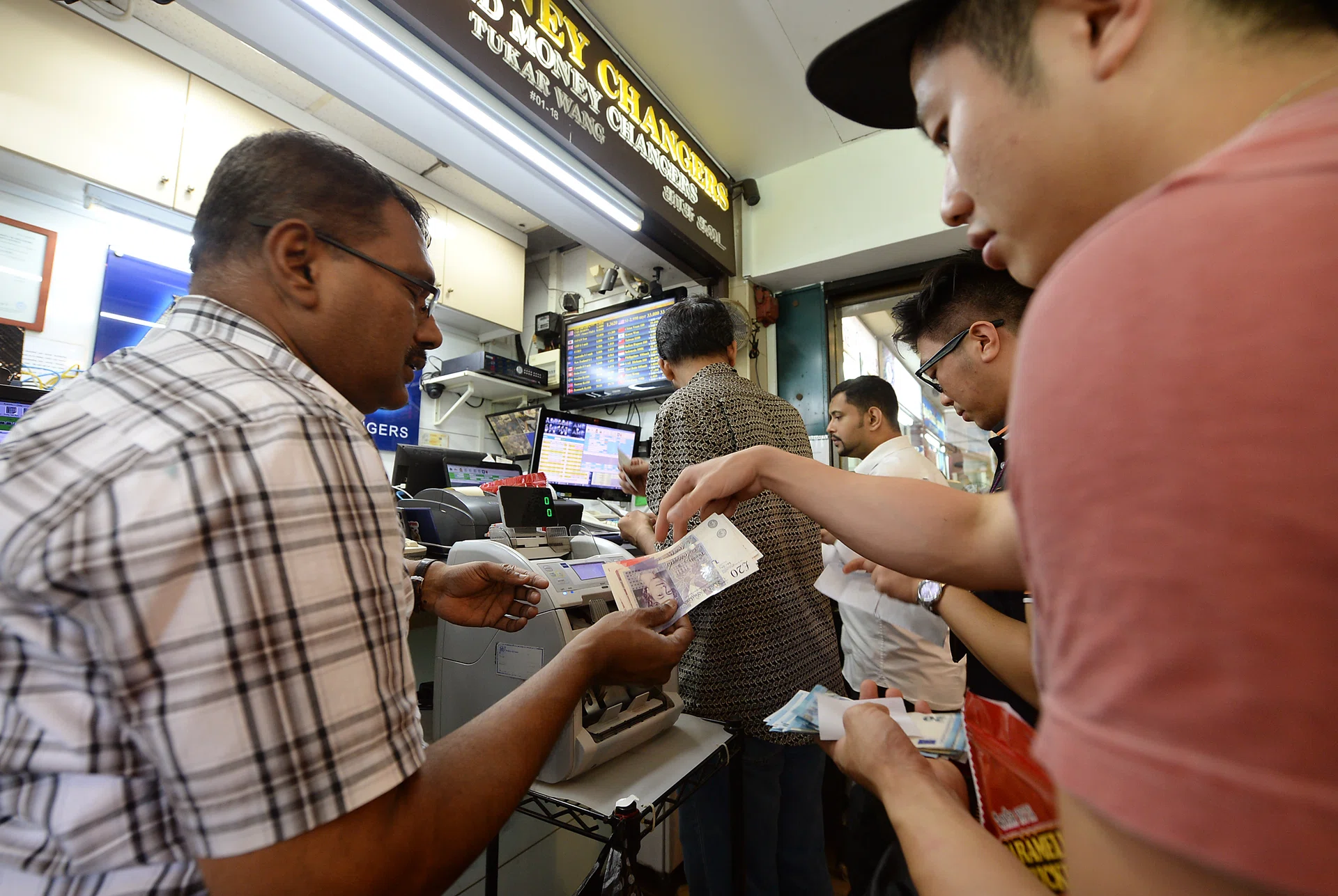 SELLING FAST: Money changers at The Arcade in Raffles Place doing a brisk trade yesterday. 