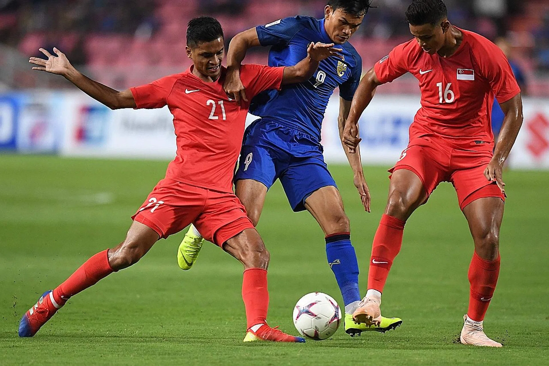 Thailand striker Adisak Kraisorn (centre) facing the challenge of Singapore's Safuwan Baharudin (left) and Irfan Fandi. PHOTO: AFP
