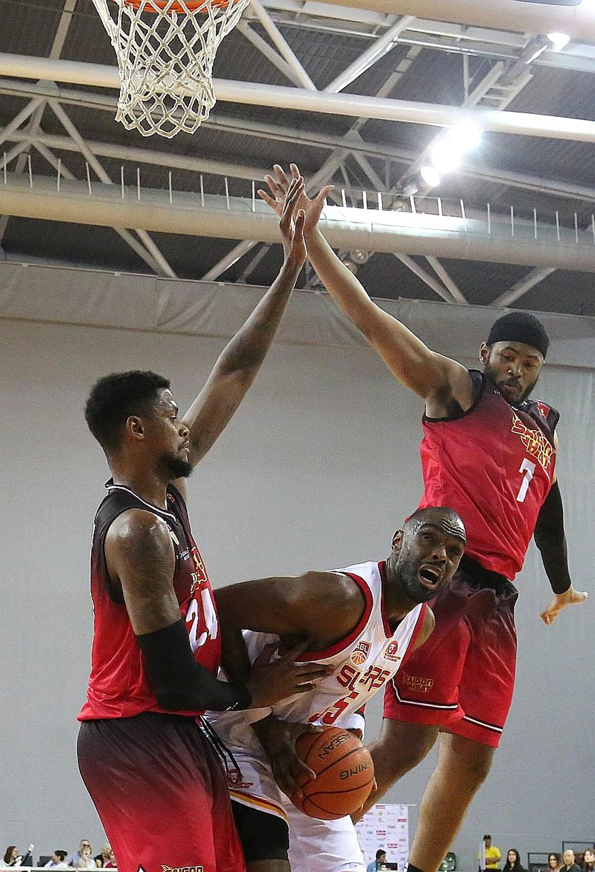 Singapore Slingers' Justin Howard (centre) found it tough under the basket yesterday in their 75-73 defeat by Saigon Heat, with the likes of Jordan Henriquez (left) and Moses Morgan (right) towering over him. 