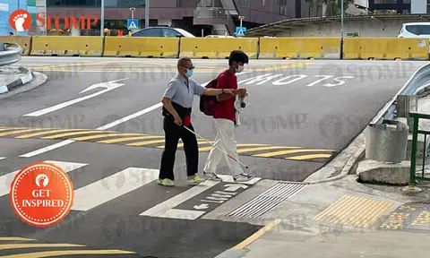 Student helps older man with white cane to safely cross busy road