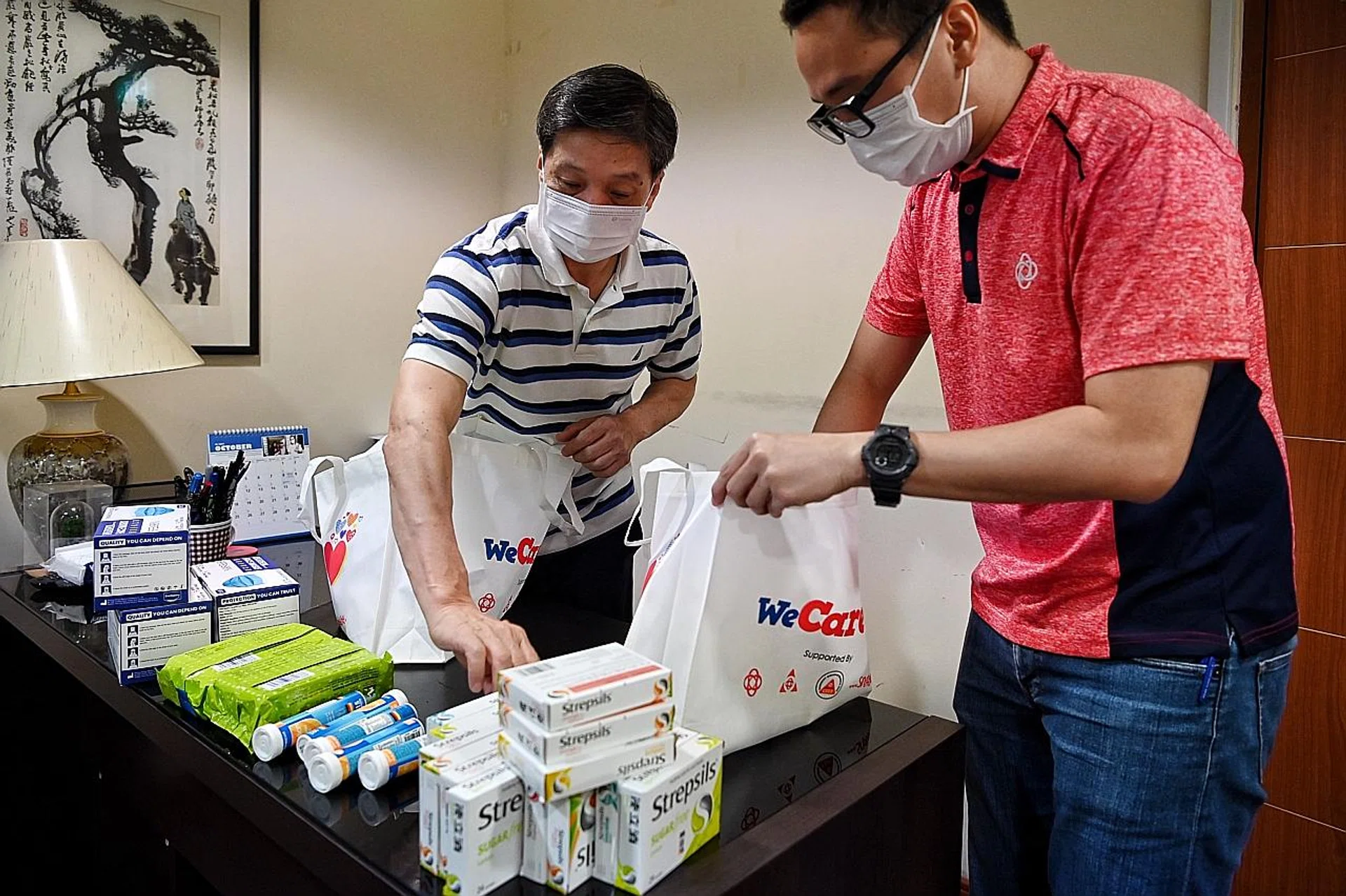 Grassroots volunteer Edwin Tay (left) and People's Association staff member Koong Chee Yong delivering care packs to Covid-19 patients on the home recovery scheme in Tampines North. 