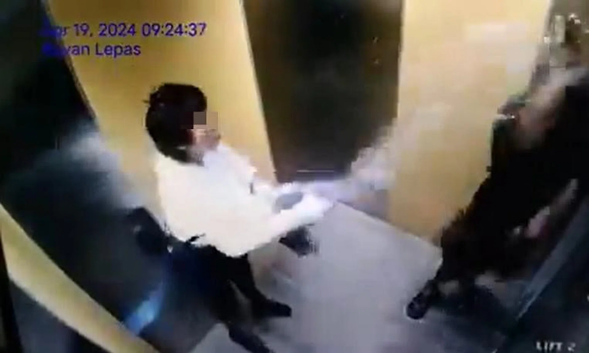 Video footage of a woman splashing water on a man in an apartment building lift.