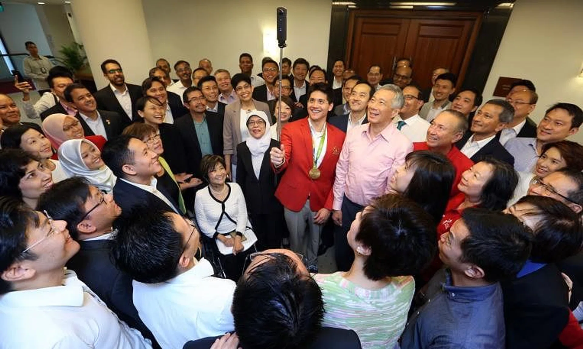 Joseph Schooling snapping a photo with PM Lee Hsien Loong and other MPs at Parliament House in 2016.