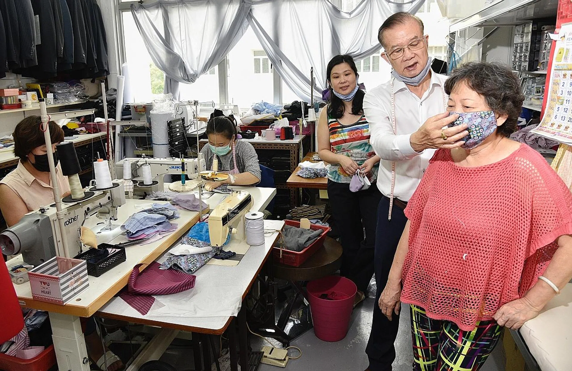 Ms Adele Chung with her father and owner of Meiko Tailor, Mr Chung Chi Kwong, and mother, Madam Saw Yock Lan, at their Geylang East factory, which has converted into a mask-making facility. 