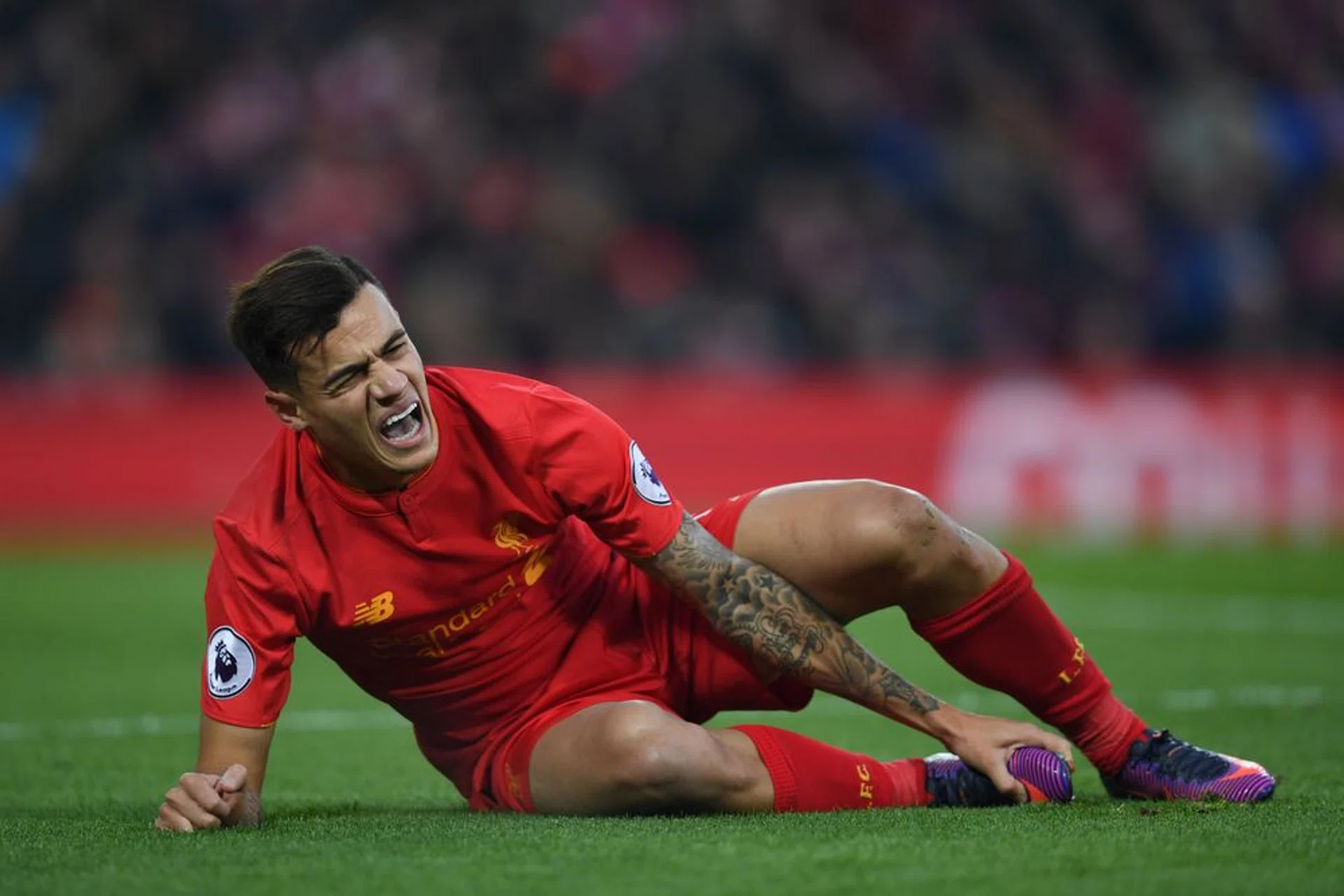 Liverpool's Brazilian midfielder Philippe Coutinho holds his foot as he lies on the pitch injured during the English Premier League football match between Liverpool and Sunderland at Anfield on Saturday. 