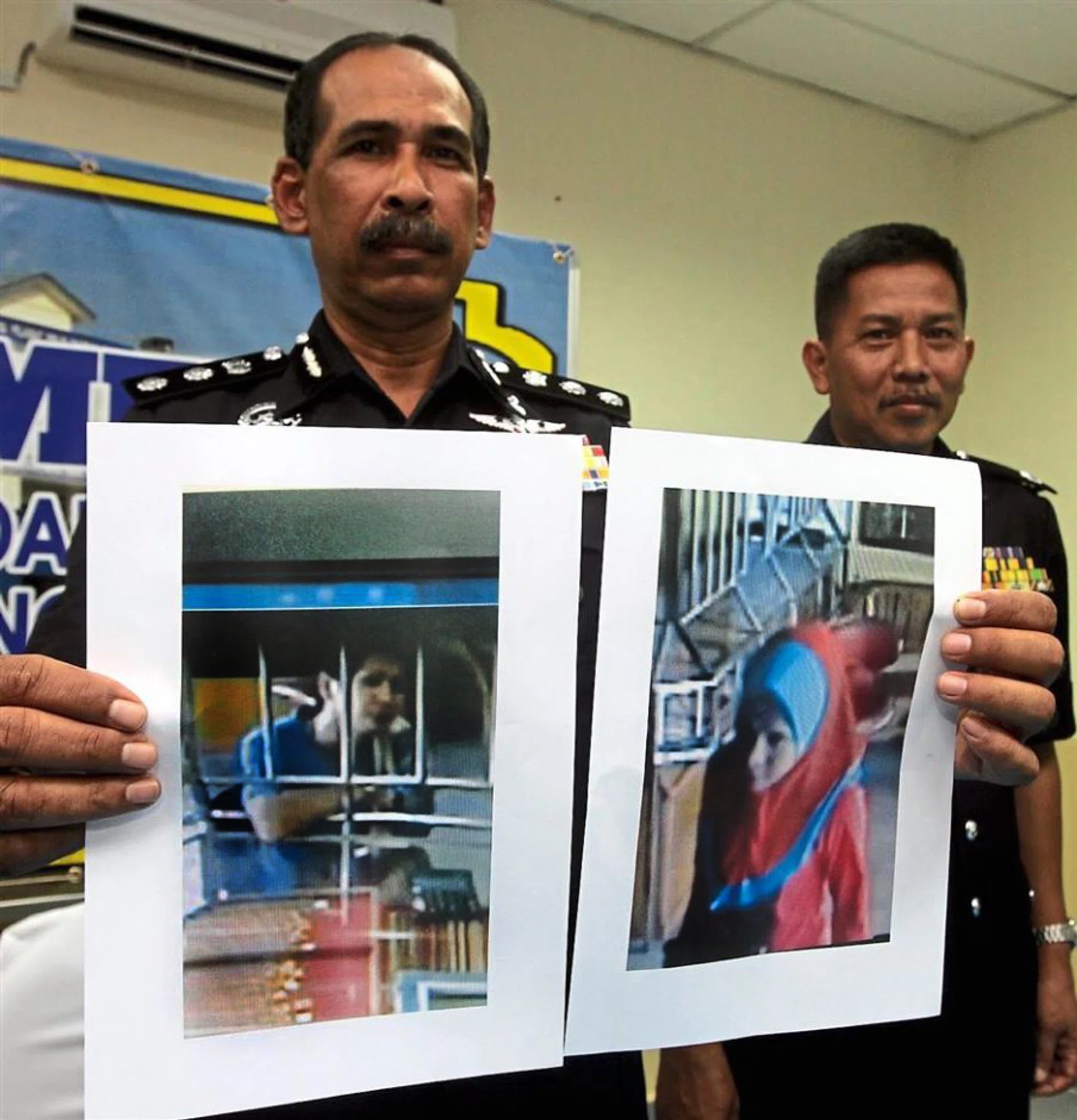 Malaysian police holding up photographs of the suspect in men's clothing (left) and in women's clothing (right).
