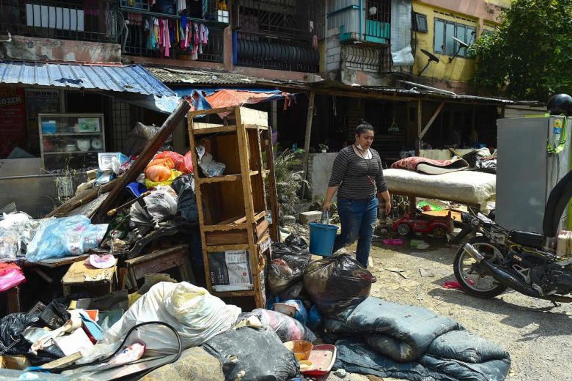 A woman walking past items salvaged from her house, which was damaged during the floods in Shah Alam, Selangor, on Dec 27, 2021.