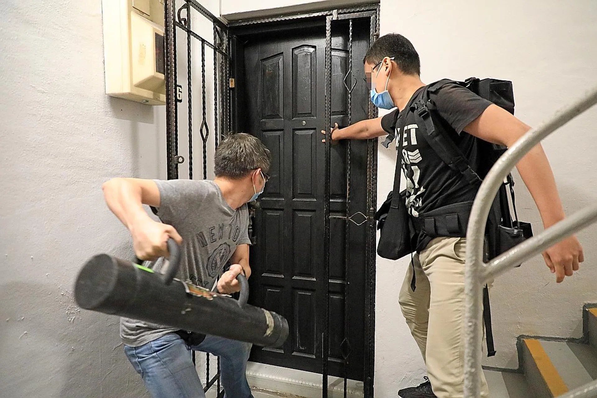 Officers using a battering ram to enter a unit in Chay Yan Street in Tiong Bahru on Saturday night. A woman was among three people arrested in the flat. PHOTO: SHIN MIN DAILY NEWS