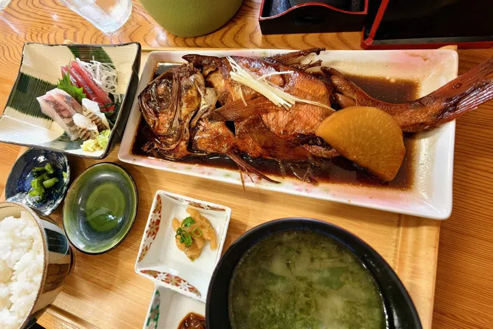 A delicious Japanese lunch featuring braised kinmedai (golden-eye snapper), a deep-sea fish native to the waters off the Izu Peninsula, served with seasonal accompaniments in a traditional setting during the Grand Seiko Ushio Journey.