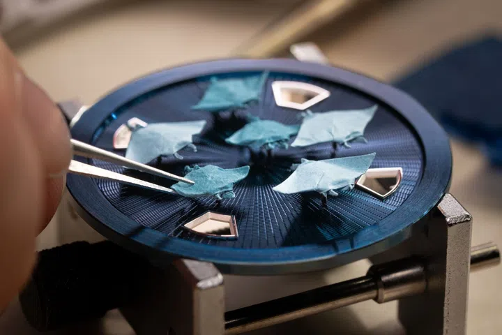 Close-up of the Vacheron Constantin Oraygami watch showing six blue micro-origami manta rays folded from Japanese paper above a hand-guilloché gold dial.
