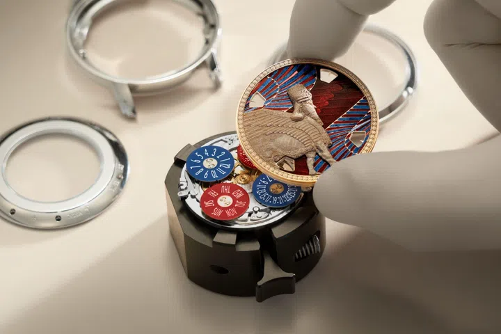 Artisan assembling the Vacheron Constantin Métiers d’Art Lamassu de Sargon II dial onto the calibre 2460 G4/2 movement, revealing the intricate stone carving, translucent red enamel, and aperture display system.