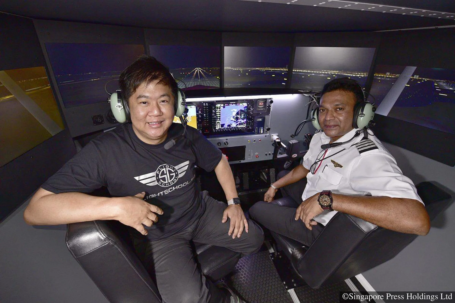 Fabian Lim (left), co-founder of FlightSchool. sg, which uses a flight simulator to conduct flight training. He is with Captain Saravanan Sukomaran, an instructor at the school. PHOTO: SPH / Desmond Wee