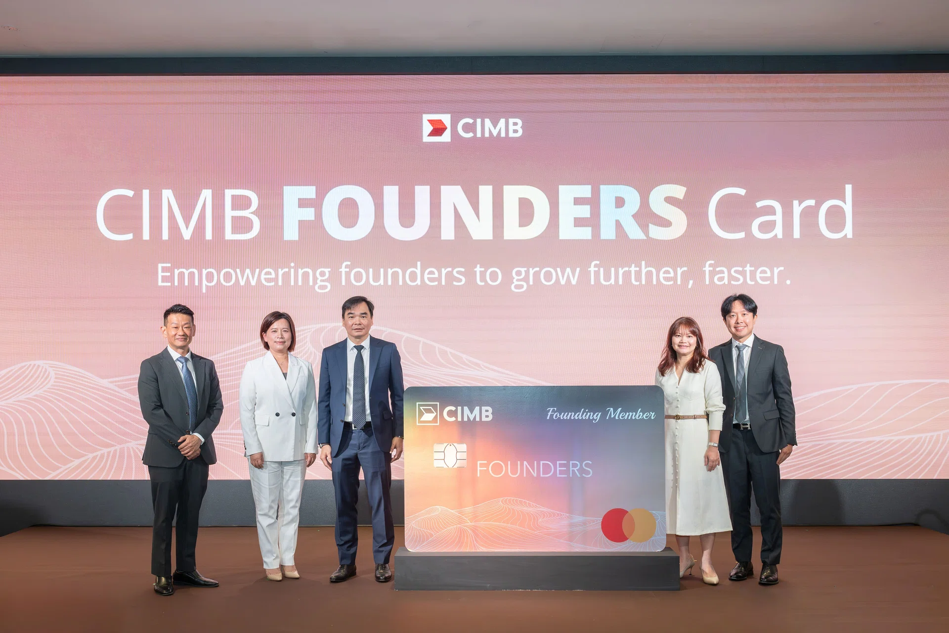 Five people in business attire stand around a enlarged version of the CIMB Founders Credit Card