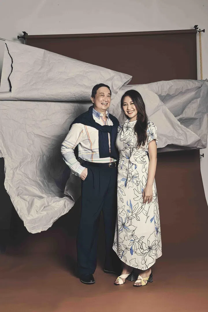 Anna is wearing a white silk floral prints dress from Hugo and leather heels from Jimmy Choo. Anna's father is wearing a striped cotton shirt and navy blue cotton knit pullover from Polo Ralph Lauren.