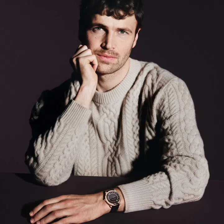 Model wearing the Van Cleef & Arpels Midnight Heure d’Ici & Heure d’ailleurs watch, showcasing the 38mm rose-gold case, amber enamel dial with twin jumping-hour displays, and retrograde minute indication on the wrist.