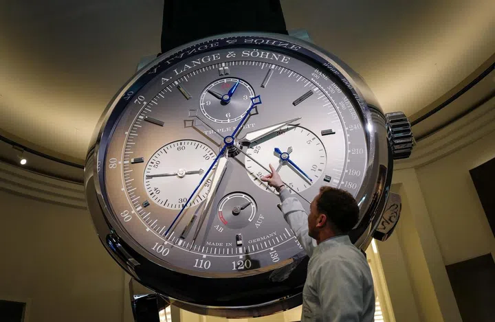 Photo: Fabrice Coffrini / AFP A staff gestures next to a giant watch at the stand of German watchmaker A. Lange & Soehne, owned by the Richemont group, during the 28th International Fine Watchmaking Exhibition SIHH, on January 18, 2018 in Geneva. (Photo by Fabrice COFFRINI / AFP)