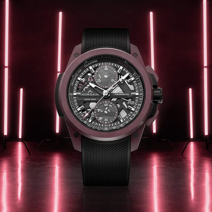 Norqain Wild One Skeleton Chrono in a burgundy Norteq case with a skeletonised dial, transparent chronograph discs, matching rubber strap, and black shock-absorbing core.