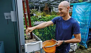 Future Protein Solutions CEO Christopher Leow scatters cricket frass on plants, which will be fed to crickets, creating a circular economy.