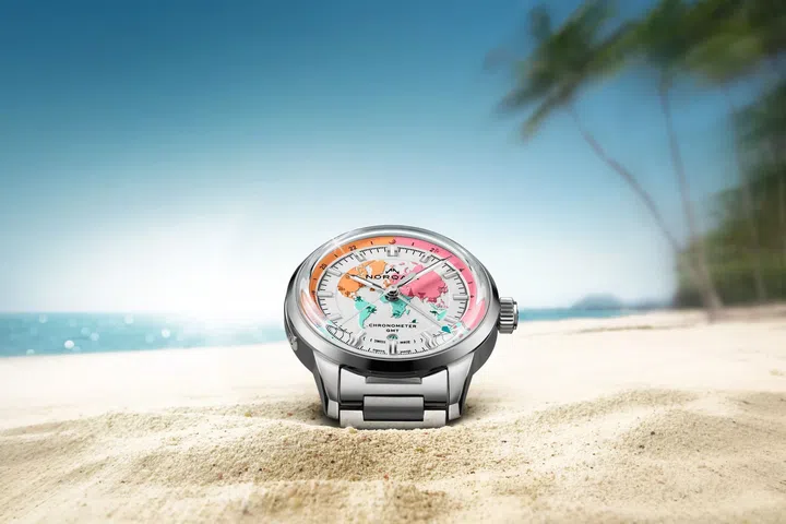 The Norqain Freedom GMT Enjoy Life “Holiday” Limited Edition rests on white sand by crystal-clear turquoise waters at Ayada Maldives resort.