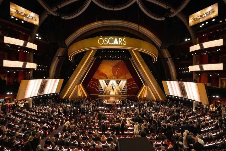 Wide view of the 98th Oscars ceremony at the Dolby Theatre in Hollywood, with the illuminated stage framed by sweeping gold architectural elements.