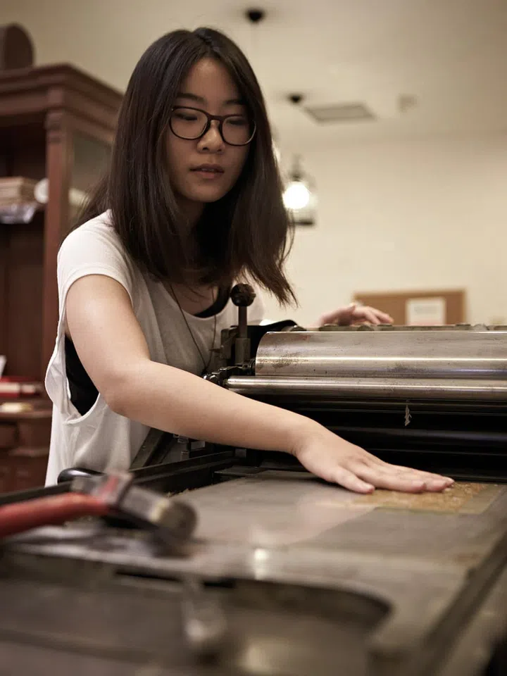 Michelle develops her designs using various printing mediums, illustrations and types. She then arranges the types, which can go as small as eight points, and places them in galleys before locking them in place in a frame. Low-height pieces of wood or metal furniture are used for the blank areas. Lastly, she mixes the ink by hand to achieve the right colour, and applies it to the type and plates before feeding the paper. The ink is reapplied regularly for a consistent tone.
