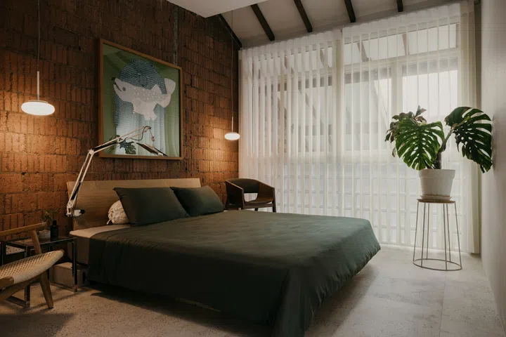 The exposed brick of the party wall and glass breezeblocks give the master bedroom a 70s vibe. (Photo: Studio Periphery)