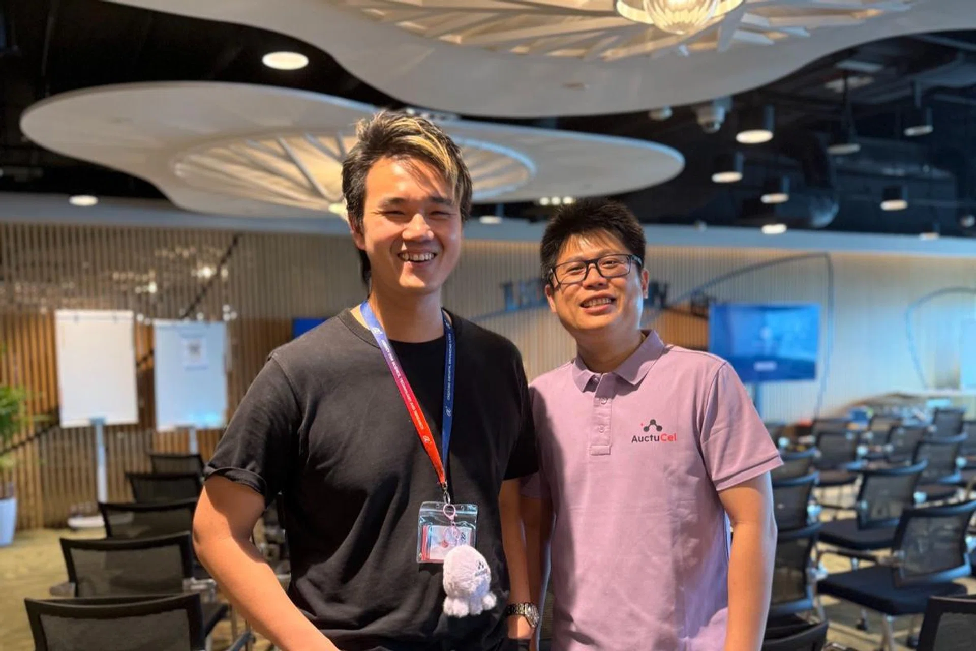 The two founders of AuctuCel stand side by side in a conference room, Zach Pang on the left, Chee Wai Fhu on the right.