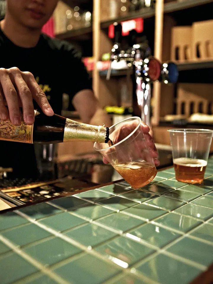 Edward Tan pours out Lindeman's' peach lambic beer from Belgium.