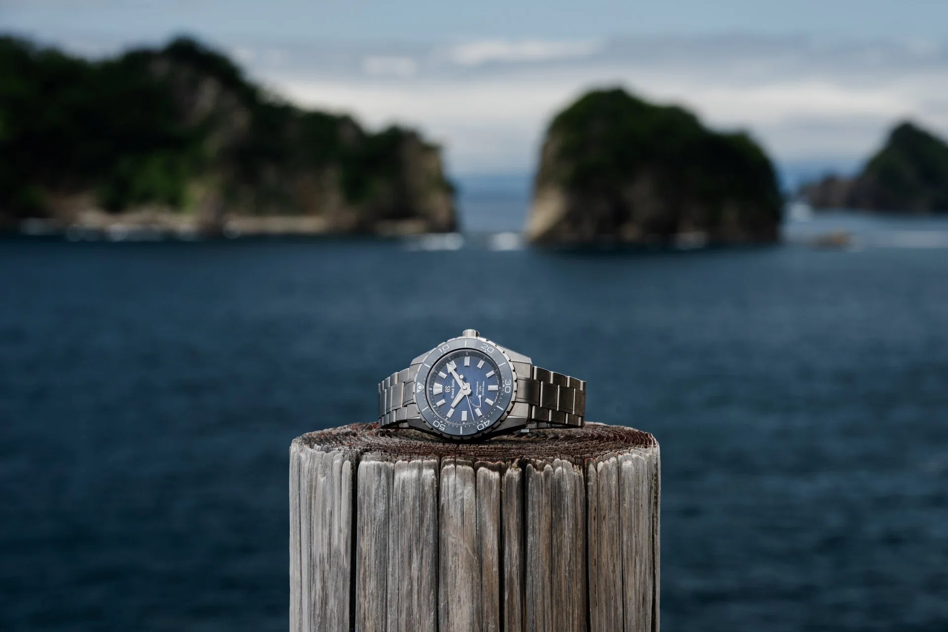 The Grand Seiko Evolution 9 Collection Spring Drive U.F.A. Ushio 300 Diver (SLGB023) in High-Intensity Titanium, featuring a 40.8mm case, deep blue gradient Ushio-pattern dial inspired by ocean tides, unidirectional ceramic bezel, luminous faceted indexes and hands, and matching titanium bracelet.