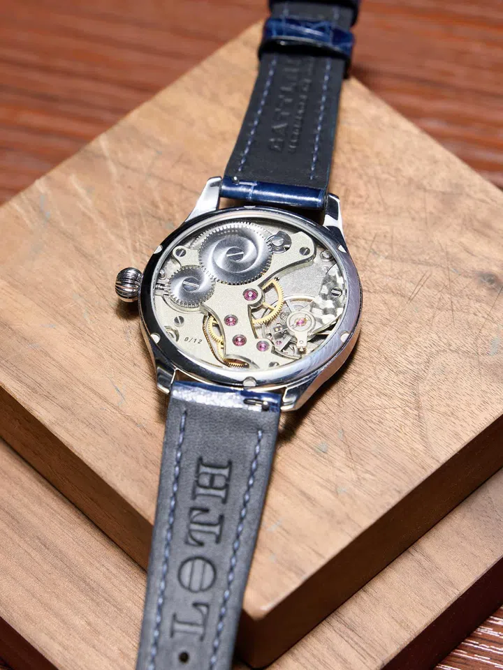 Back view of the LOTH Watch 1, revealing the mechanical movement hand-finished by founder Tristan Ho. The movement features hand-executed anglage on the bridges, black-polished steel components, straight-grained surfaces, frosted finishes, perlage on the baseplate, polished screw heads and carefully bevelled edges.
