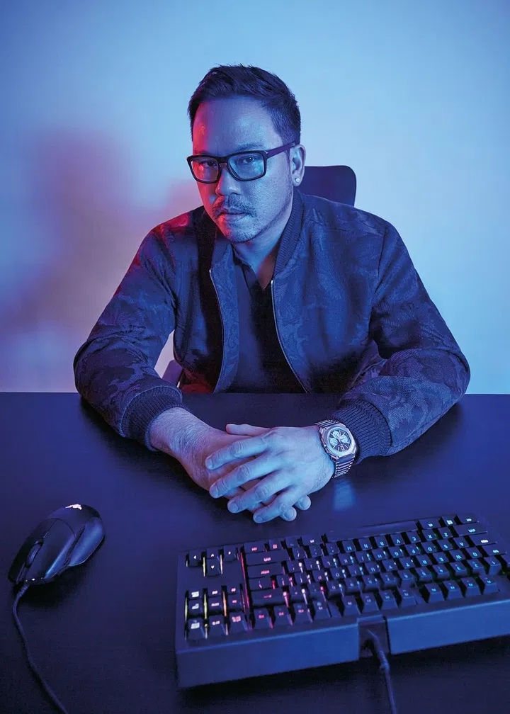Samson Oh posing with a gaming keyboard and mouse. Oh is wearing a Bvlgari chronograph.