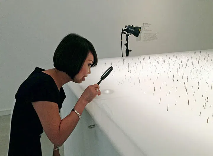 Chong examining carved wooden figurines in Cosmology Of Life by Indonesian artist Toni Kanwa at Singapore Art Museum. Some of them are smaller than a grain of rice.