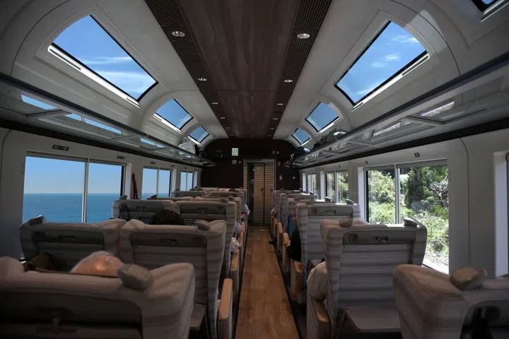 Interior of the Saphir Odoriko luxury sightseeing train in Japan, featuring elegant wood-panelled cabins, spacious seating, large panoramic windows and refined interiors designed for scenic journeys between Tokyo and the Izu Peninsula.