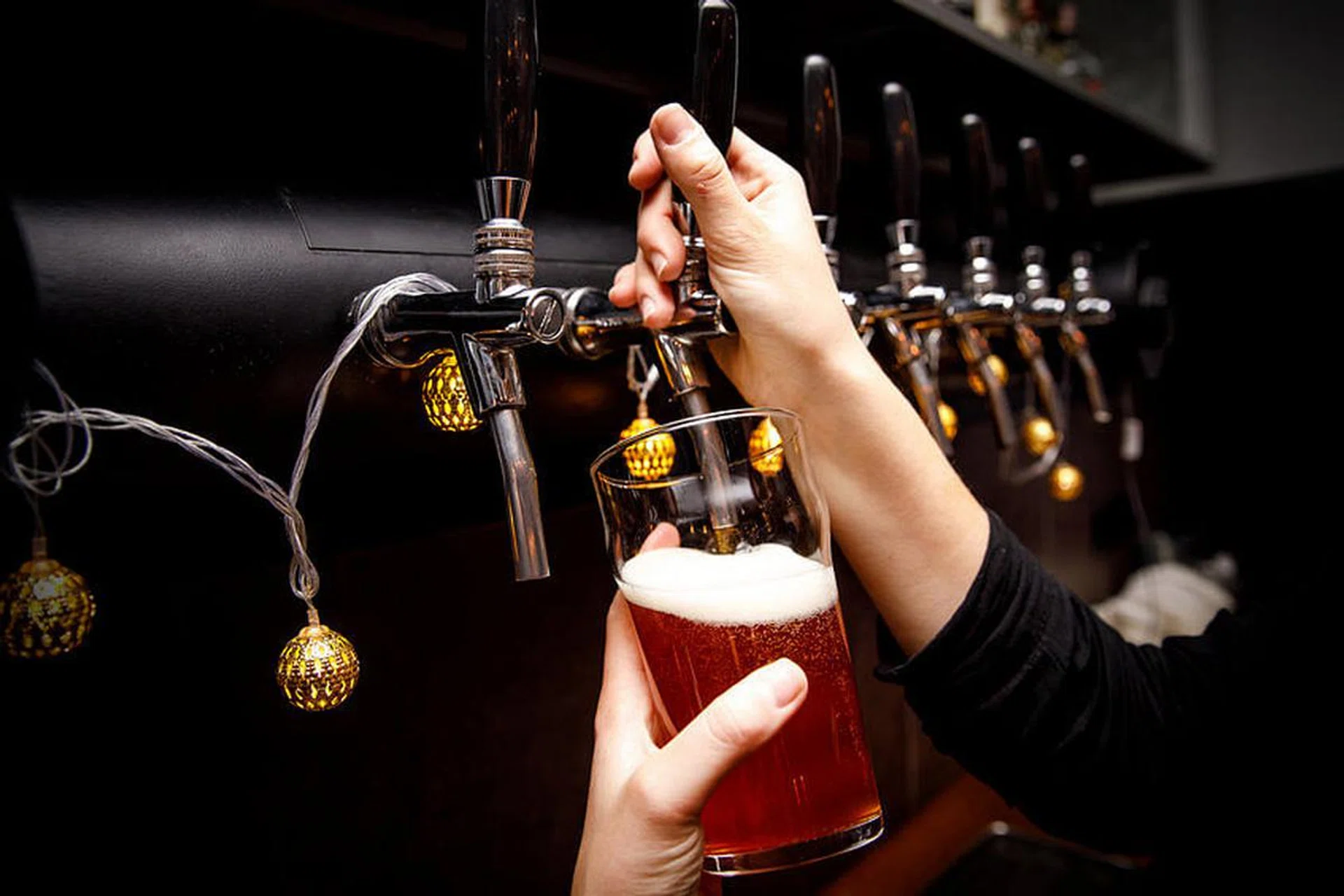 Bartender pours fresh ale from tap in tap.