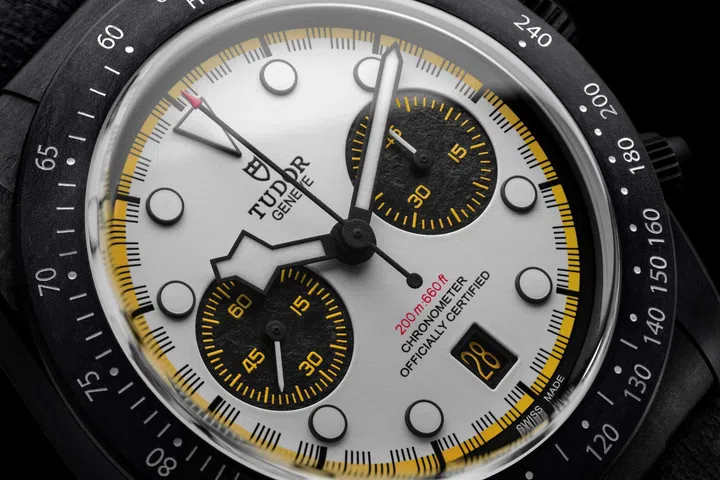 Close-up of the Tudor Black Bay Chrono “Carbon 26” with a racing-white dial, yellow accents, carbon-fibre case and black chronograph counters.