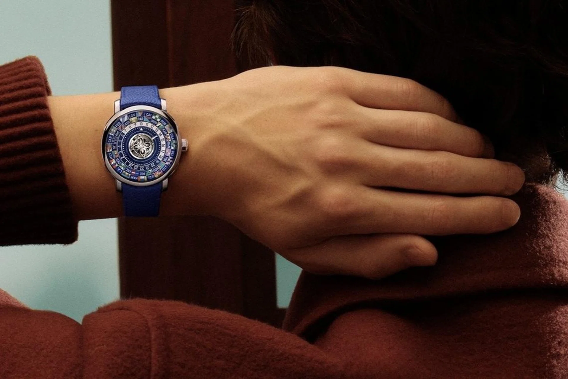 The Louis Vuitton Escale Worldtime Tourbillon in platinum, showcasing a grand feu enamel world-time display encircling a central flying tourbillon shaped like the Monogram Flower, paired with a blue leather strap.