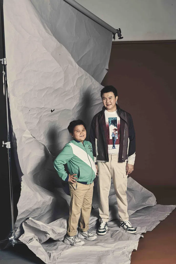 Lester is wearing a cotton printed t-shirt, #UseTheExisting soft shell jacket andivory cotton cargo pants from Z Zegna. His white & green leather sneakers are from Jimmy Choo. His son is wearing a green cotton jacket and khaki cotton chino pants from Polo Ralph Lauren.