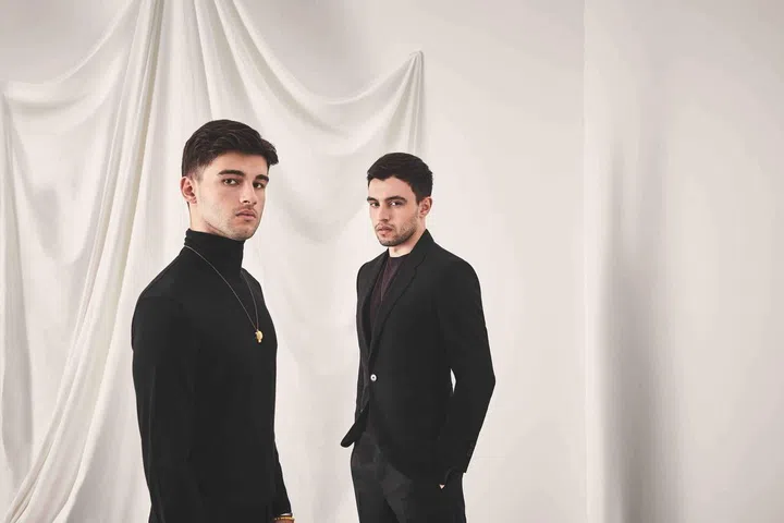 Rogerio Calisto (left) is wearing a black viscose turtleneck from Bottega Veneta. Gabriel is wearing a a maroon wool pullover and a black silk suit from Ermenegildo Zegna.