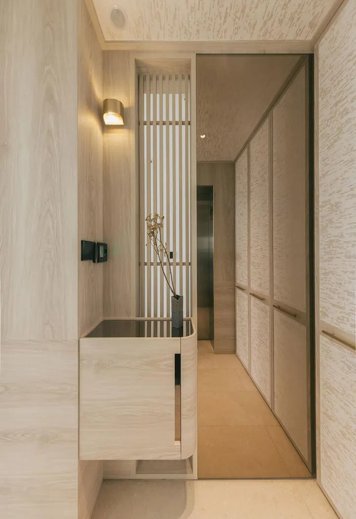 In the entry vestibule, light filters in through vertical louvres. On the right, the shoe cabinet is concealed behind panels decorated with handmade wallcovering. (Photo: Finbarr Fallon, courtesy of Parenthesis Studio)
