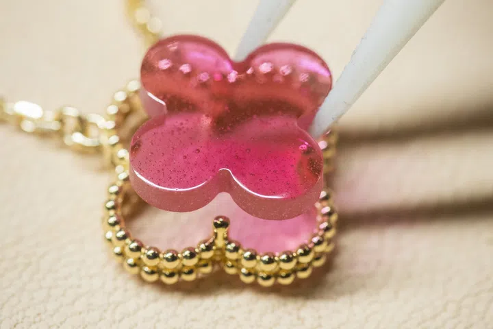 Close-up of the Van Cleef & Arpels Vintage Alhambra four-leaf clover motif showcasing fine gold flecks used in the enamel production to create the vibrant pink hue